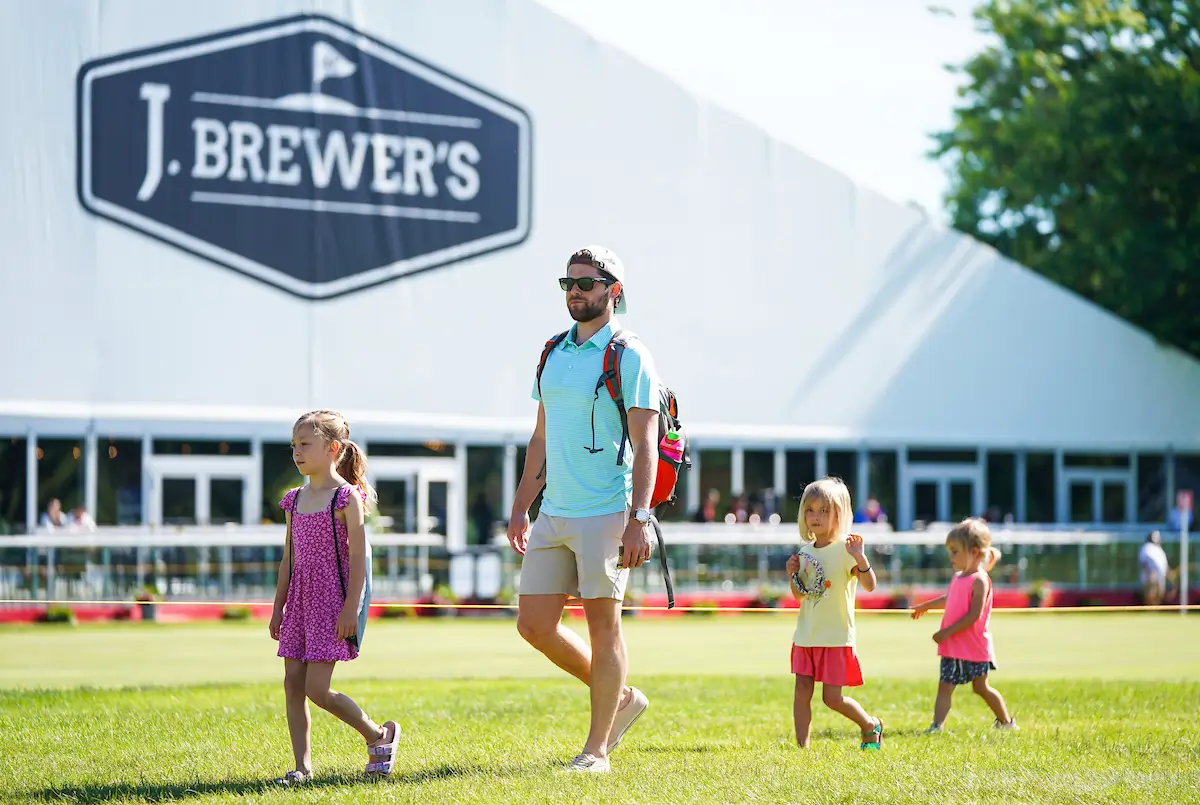 Man and 3 girls walking in grass at J Brewers