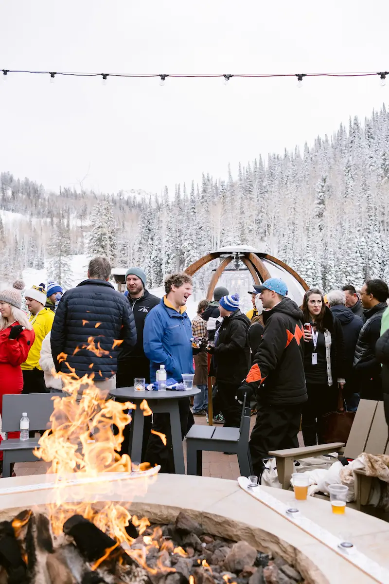 group of people socializing with snow and a fire